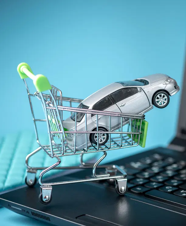 Model of a mini shopping basket with a car on a laptop keyboard.